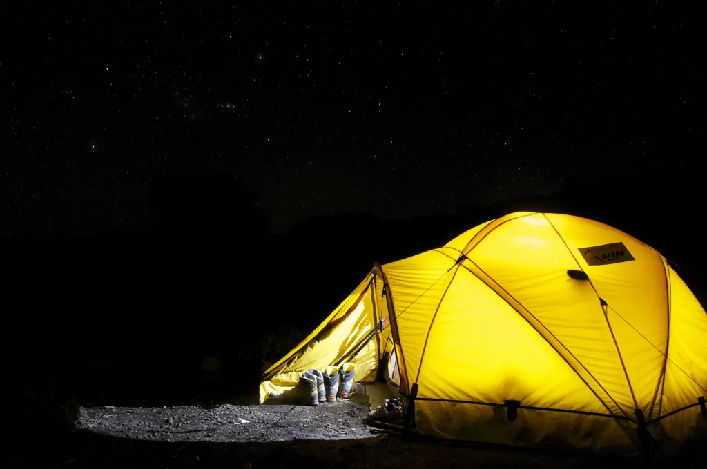Orange illuminated tent on lake in the evening